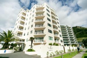 a white building with palm trees in front of it at Beaumont Apartments in Mount Maunganui
