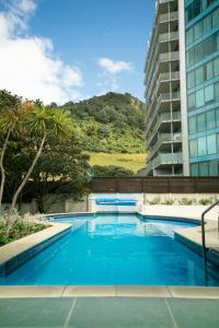 a large blue swimming pool next to a tall building at Beaumont Apartments in Mount Maunganui