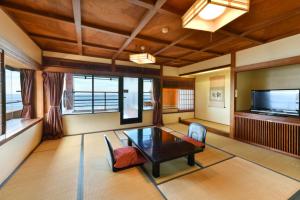 a living room with a table and a tv at Hokkawa Onsen Hotel in Higashiizu