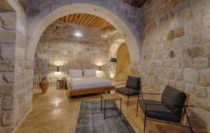 a bedroom with a bed and chairs in a stone wall at Solem Cave Suites in Urgup