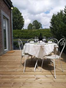 una mesa con sillas y una botella de vino en el patio en Ô'bel Écrin en Aubel