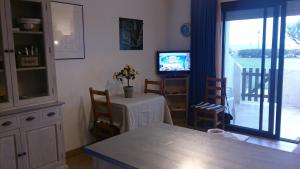a living room with a table and a television and a balcony at Stephanie Immobilier in Saintes-Maries-de-la-Mer