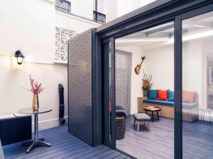 une porte coulissante en verre menant à une terrasse avec un canapé. dans l'établissement Mercure Paris Pigalle Sacre Coeur, à Paris