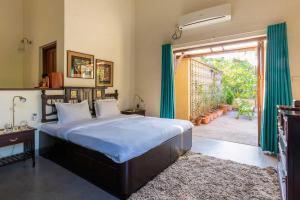 a bedroom with a large bed and a door to a patio at Villa Amaaya - The Hidden Gem by StayVista in Alibaug +28 photos