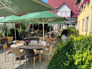 a patio with tables and chairs with green umbrellas at Landgasthof Kaiser in Bieringen