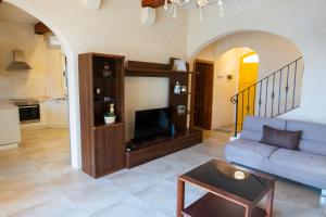 a living room with a couch and a tv at Inni Holiday Home with Infinity Pool in Għarb