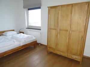 a bedroom with a bed and a wooden cabinet at Kustverhuur, Appartement aan Zee, Port Scaldis 01061 in Breskens