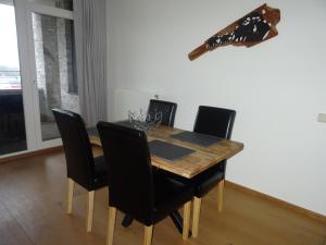 a dining room table with black chairs and a wooden table at Kustverhuur, Appartement aan Zee, Port Scaldis 01061 in Breskens