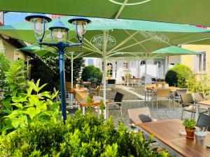 a patio with tables and chairs and a green umbrella at Landgasthof Kaiser in Bieringen