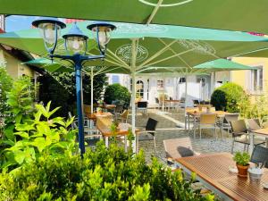 Bieringen的住宿－Landgasthof Kaiser，一个带桌椅和绿色遮阳伞的庭院