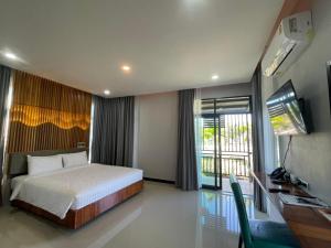 a bedroom with a bed and a desk and a television at Phutara Resort and Spa in Buriram