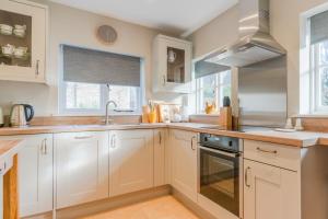 a kitchen with white cabinets and a sink at Corner Cottage in Bretforton