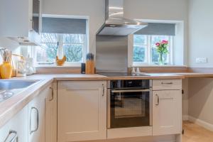 a kitchen with white cabinets and a stove top oven at Corner Cottage in Bretforton