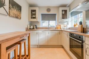 a kitchen with white cabinets and a wooden counter top at Corner Cottage in Bretforton