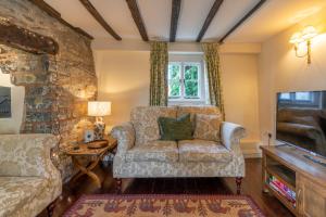 a living room with a couch and a chair at Corner Cottage in Bretforton