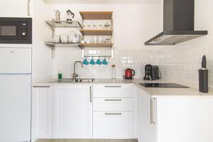une cuisine blanche avec des armoires blanches et un évier dans l'établissement Home2Book Design Las Canteras2 Beach, à Las Palmas de Gran Canaria