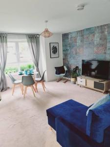 a living room with a blue couch and a tv at Stylish 2 bedroom Apartment / FREE Gated Parking in Glasgow