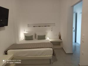 una camera da letto bianca con un letto grande e una scrivania di Kleri's apartments 6 a Città di Tinos