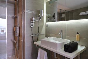 La salle de bains est pourvue d'un lavabo blanc et d'une douche. dans l'établissement L'Escale Côté Sud, à LʼÎle-Rousse