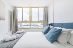 une chambre avec un lit avec des oreillers bleus et une fenêtre dans l'établissement Home2Book Design Las Canteras2 Beach, à Las Palmas de Gran Canaria
