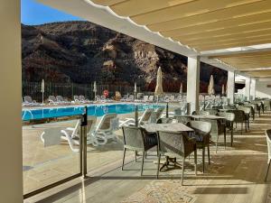 ein Restaurant mit Tischen und Stühlen neben einem Pool in der Unterkunft Apartamentos Cordial Magec Taurito in Taurito