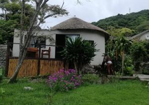 a small white house with a grass roof at Ikaya Accommodation Psj in Port St Johns