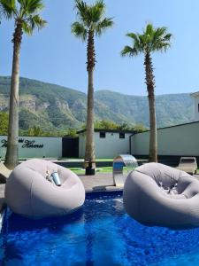 - deux grandes chaises gonflables dans une piscine bordée de palmiers dans l'établissement B&B Villa Hermes, à Sarno