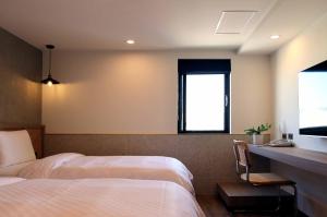 1 dormitorio con 2 camas, escritorio y ventana en Kindness Hotel - Yuanlin, en Yuanlin