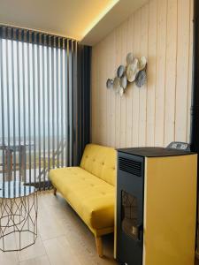 a living room with a yellow couch and a television at Cabañas Fisterra in Fisterra