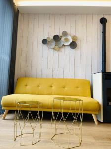 a yellow couch in a living room with two tables at Cabañas Fisterra in Fisterra