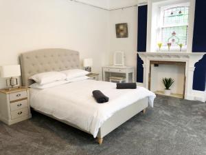 ein Schlafzimmer mit einem großen weißen Bett und einem Kamin in der Unterkunft Summer Breeze. 3-bed apartment close to the beach in Bournemouth