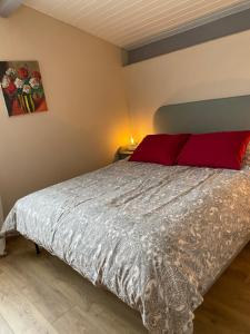 a bedroom with a large bed with a red pillow at Le Jasmin in Montcaret