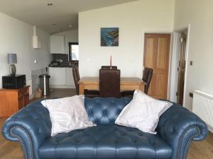 a blue leather couch in a living room with a table at Silver Strand Chalets - Chalet 1 in Glencolumbkille