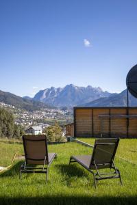 dos sillas en el césped con montañas en el fondo en Giallo Dolomiti Wellness en Pieve di Cadore