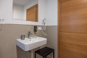 uma casa de banho com um lavatório e um telefone na parede em Giallo Dolomiti Wellness em Pieve di Cadore