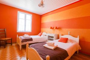 two beds in a room with orange walls at Charmante maison pour 10 personnes in Le Bois-Plage-en-Ré