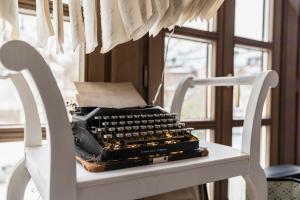 a typewriter sitting on a white chair in front of a window at Villa Fantasia Budget Boutique Hotel in Füssen