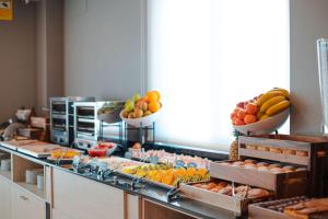 una línea de buffet con cuencos de frutas y hortalizas en Hotel Monte Rozas en Las Rozas de Madrid