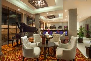 ein Restaurant mit einem Klavier, einem Tisch und Stühlen in der Unterkunft Padjadjaran Suites Resort and Convention Hotel in Bogor