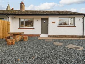 a white house with a bench in front of it at Woodview in Pooley Bridge