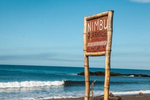 un panneau sur la plage à côté de l'océan dans l'établissement Nimbu Beachhouse, à Transito