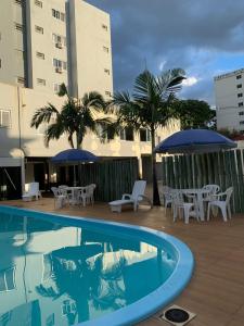 a swimming pool with chairs and umbrellas next to a building at Moura Palace Hotel in Foz do Iguaçu