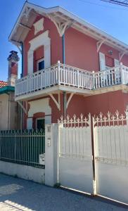 una casa rosa con una valla blanca y una puerta en Villa Yollande, en Arcachon