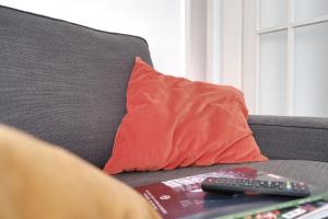 a red pillow sitting on a couch with a remote control at Ferienwohnung Speldorf in Mülheim an der Ruhr