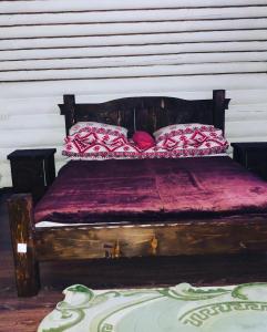 a wooden bed with red pillows on top of it at У Віти котедж 1 in Synevyrsʼka Polyana