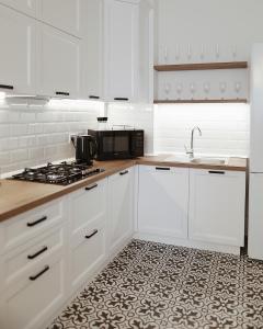 uma cozinha com armários brancos, um lavatório e um fogão em Kostjukowski Apartments Forum em Lviv