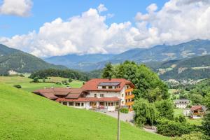 ein Haus auf einem Hügel mit Bergen im Hintergrund in der Unterkunft Hotel Pichlerhof in St. Lorenzen