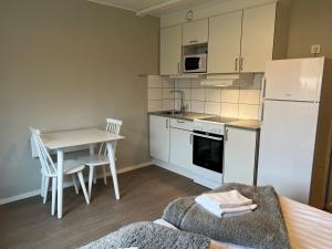a kitchen with a white refrigerator and a table with chairs at Birkagatan - Visby Lägenhetshotell in Visby