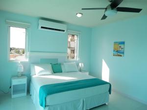 a blue bedroom with a bed and a ceiling fan at Oistins Bayview Apartments in Christ Church