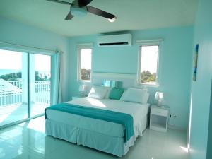 a blue bedroom with a bed and a ceiling fan at Oistins Bayview Apartments in Christ Church +26 photos